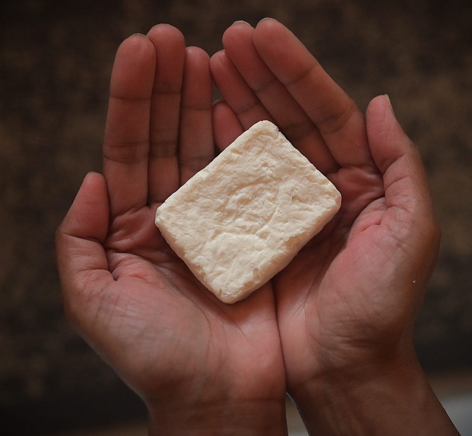 Two cupped hands holding a bar of Relavco soap.