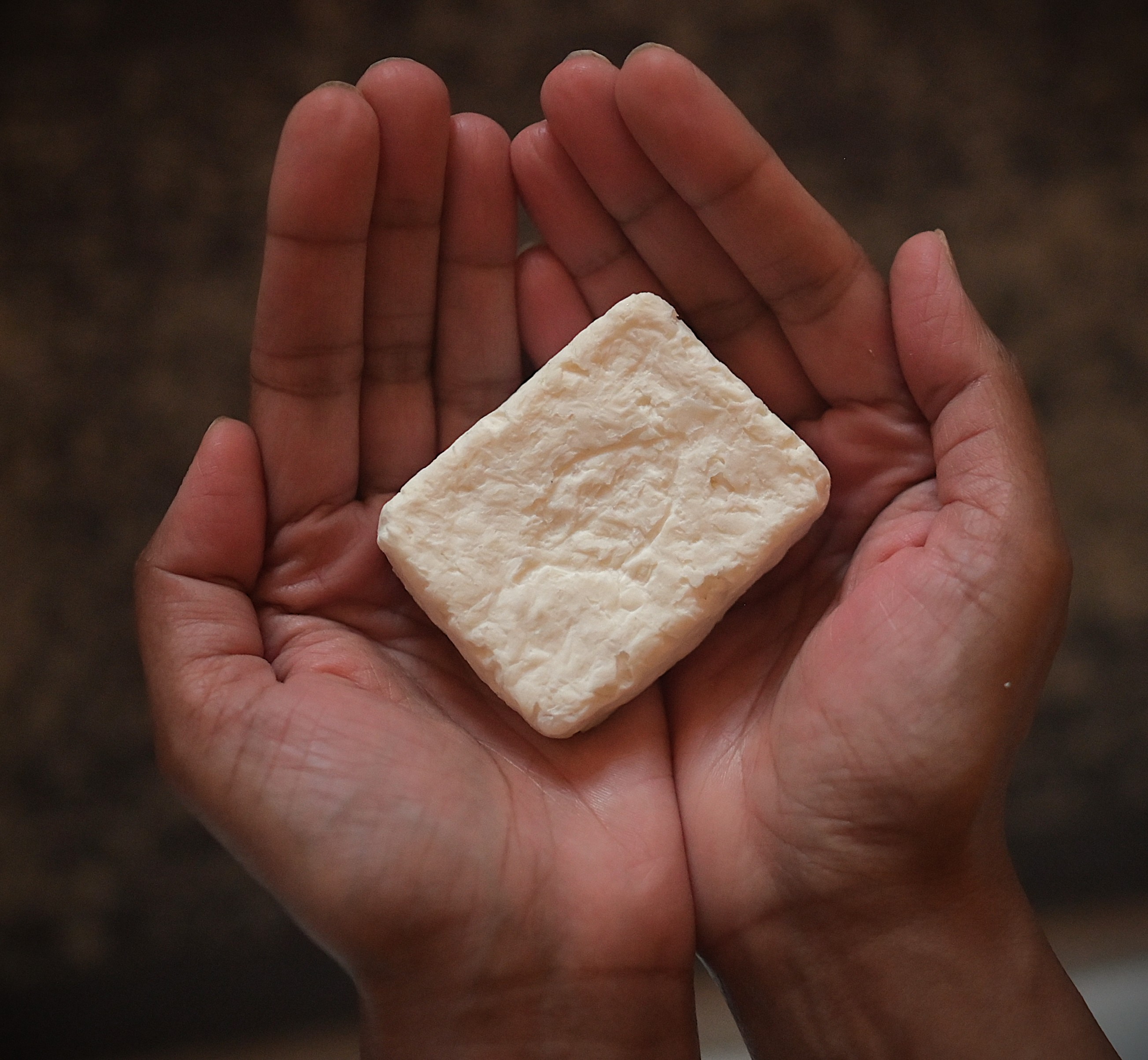 Two cupped hands holding a bar of Relavco soap.