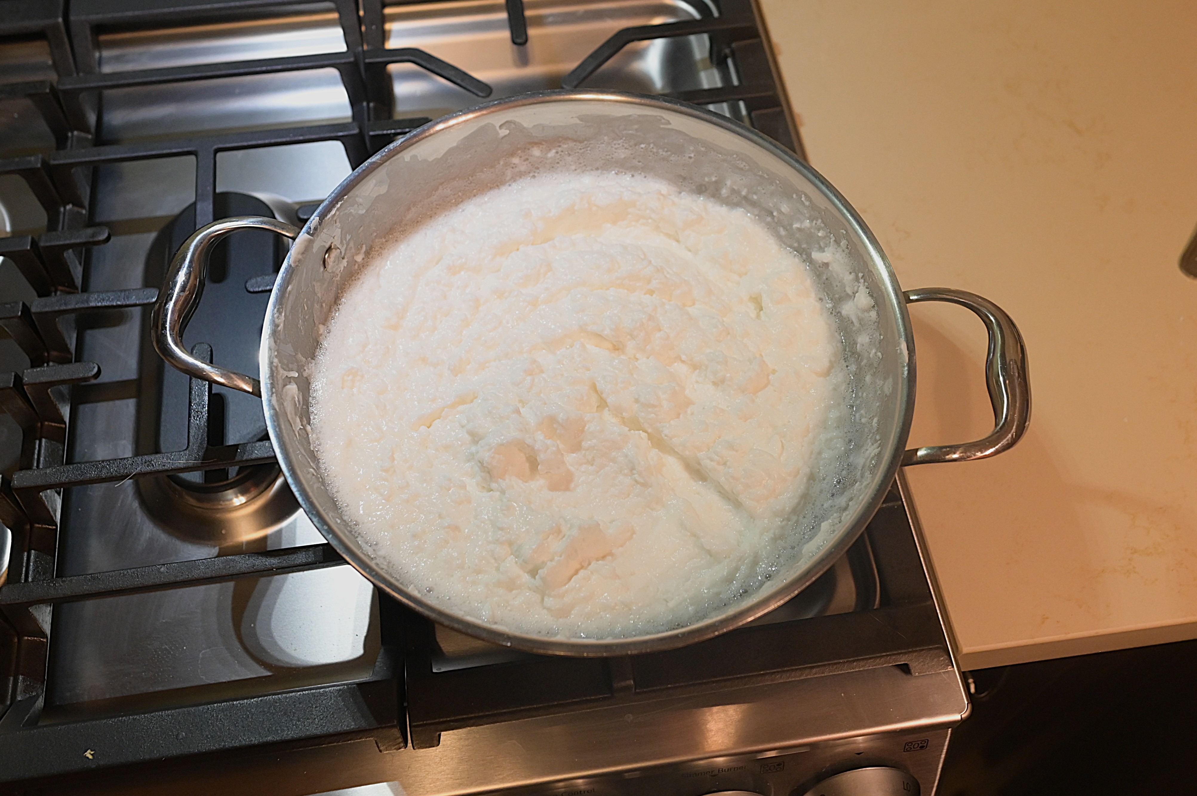 Photo: warm melted soap base being stirred in a pot, steam rising.